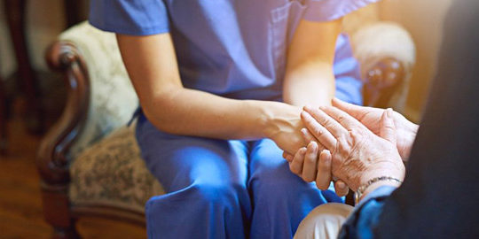 enfermera y anciana se dan la mano